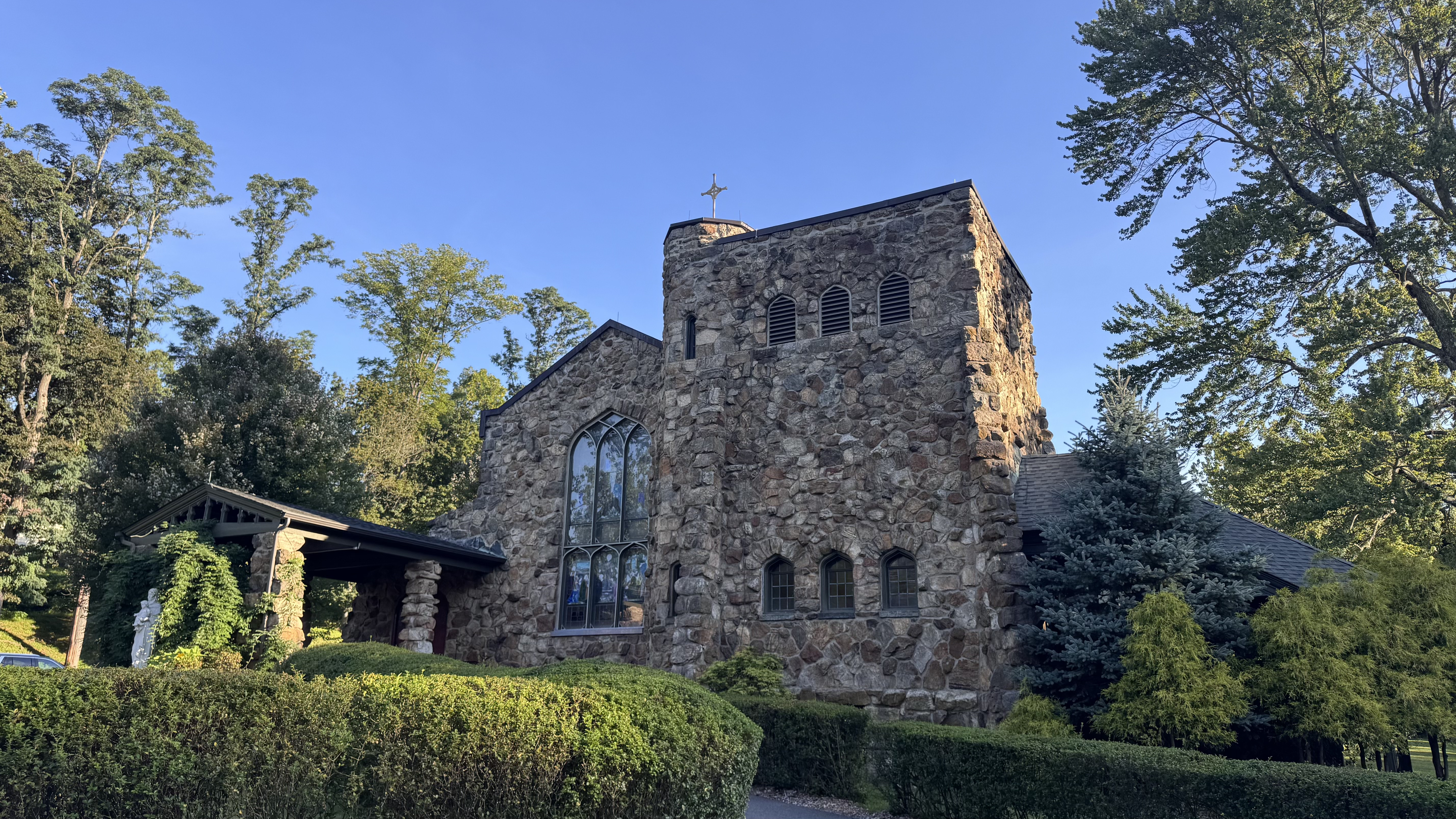 The stone exterior of Our Lady of Perpetual Help surrounded by trees